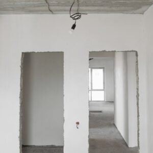 Unfinished room interior with white plastered walls and exposed ceiling in a construction site.
